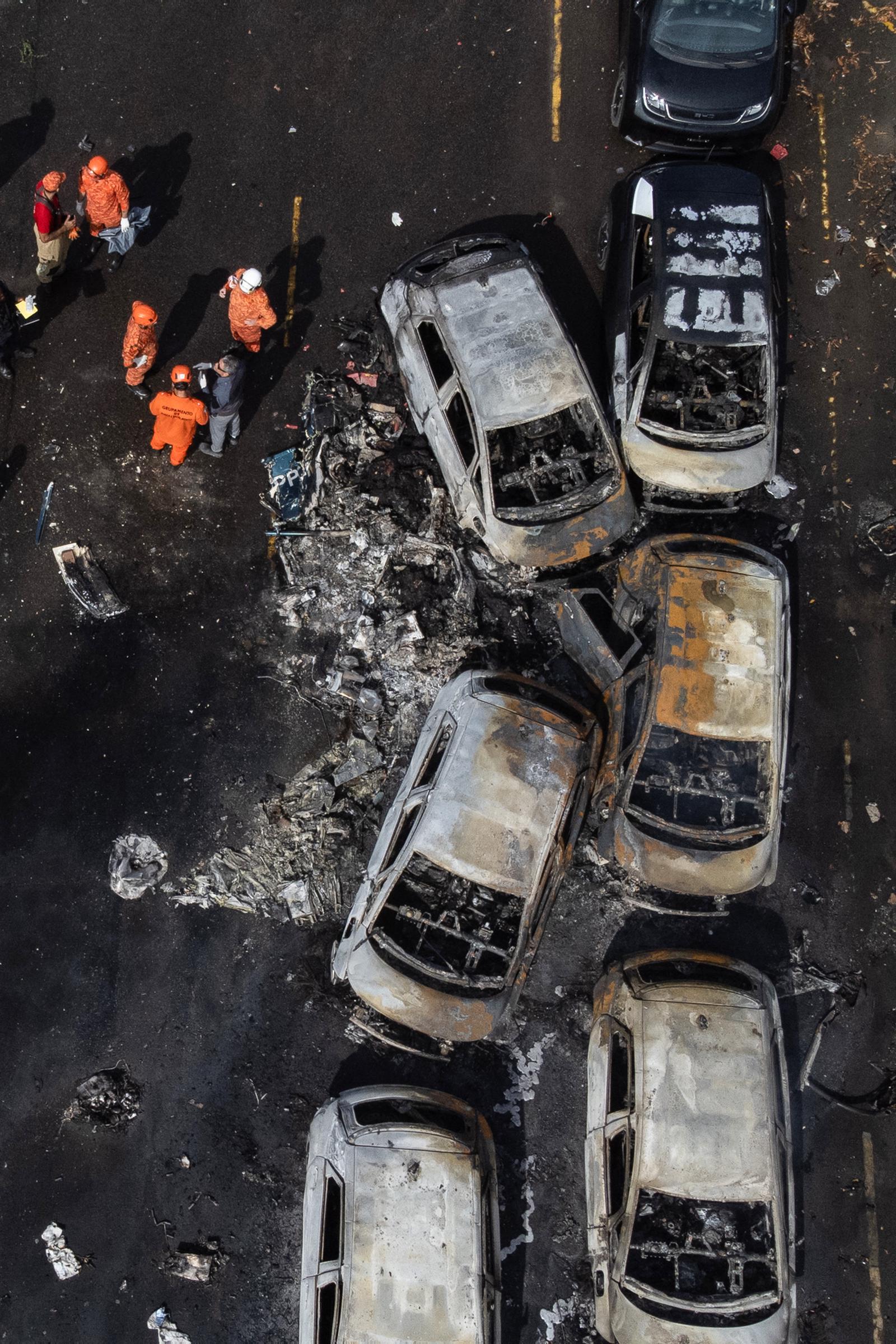 Investigators documented the damage from above after the helicopters crashed into a vehicle yard in Rio de Janeiro. The collision left burned vehicles and debris scattered across the scene. | Source: Getty Images